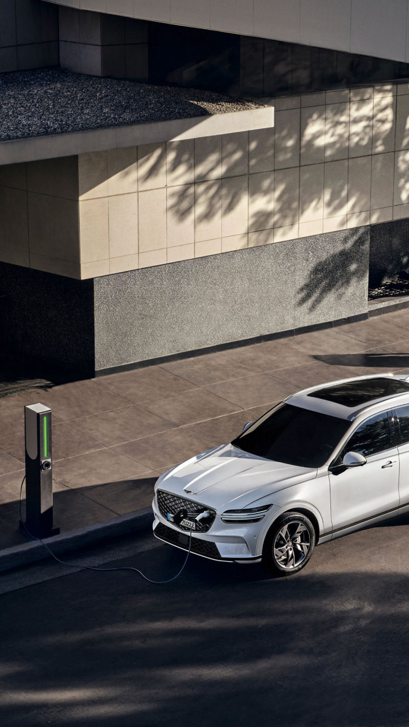 An aerial view of the Genesis Electrified GV70 parked at a public charging station