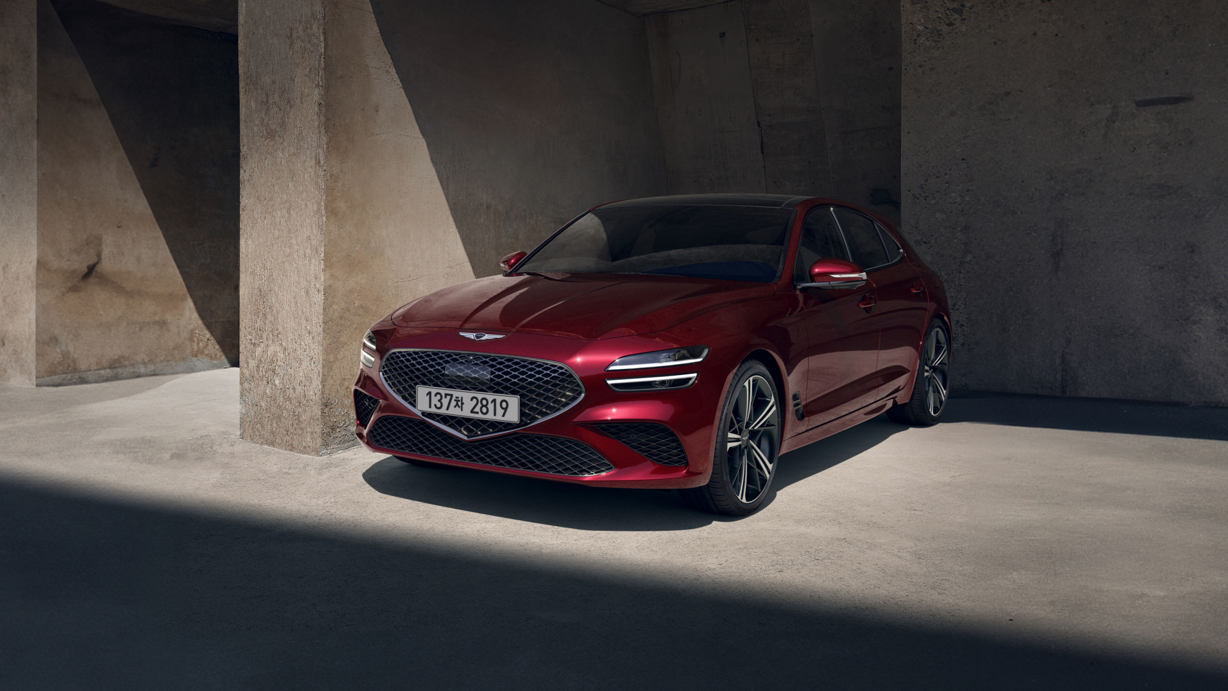 The G70 Shooting Brake in vibrant red, parked under soft sunlight, highlighting its bold front grille and sharp headlights.