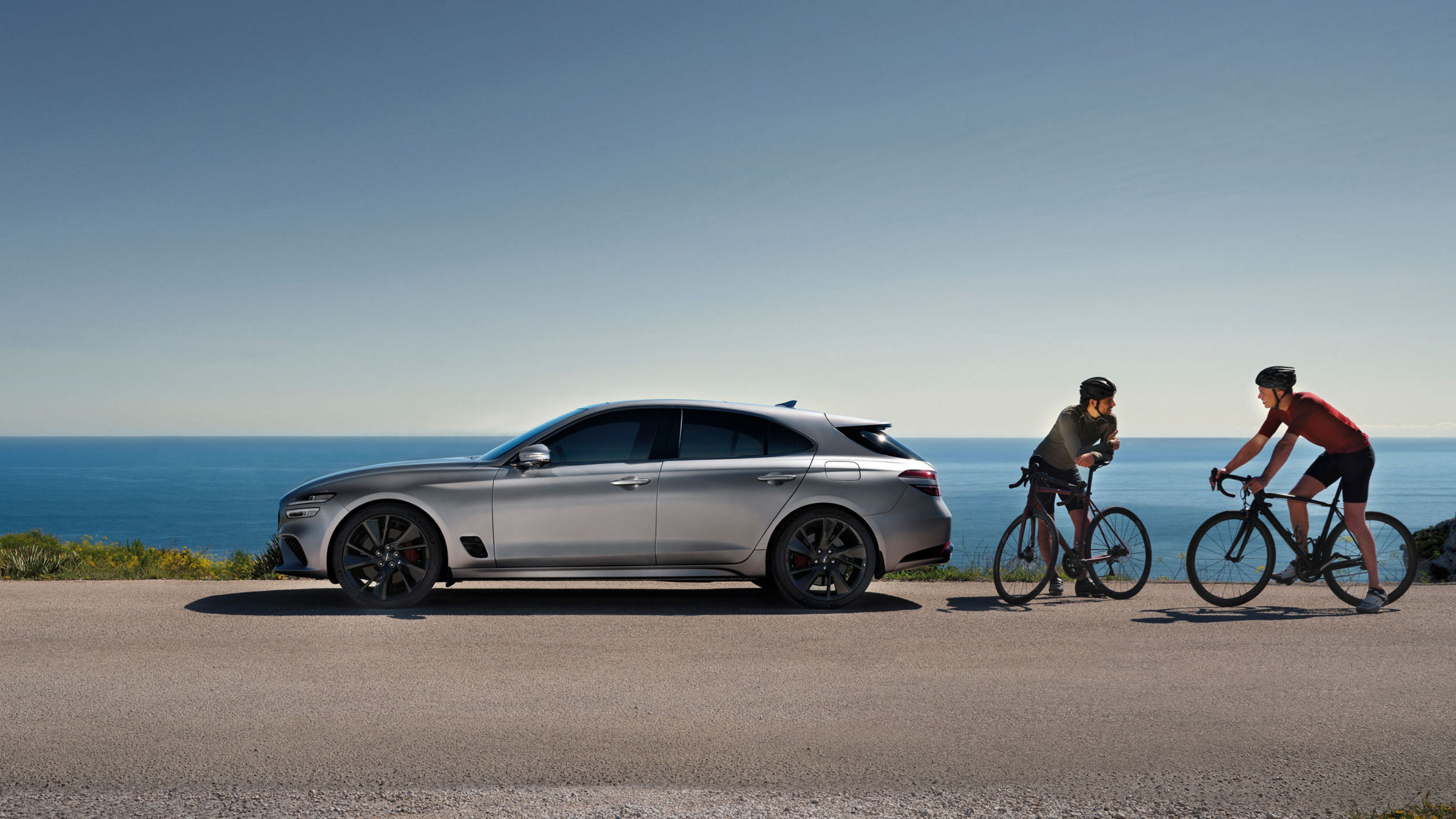 The G70 Shooting Brake parked by the coast with two cyclists nearby, highlighting its sporty and elegant design.