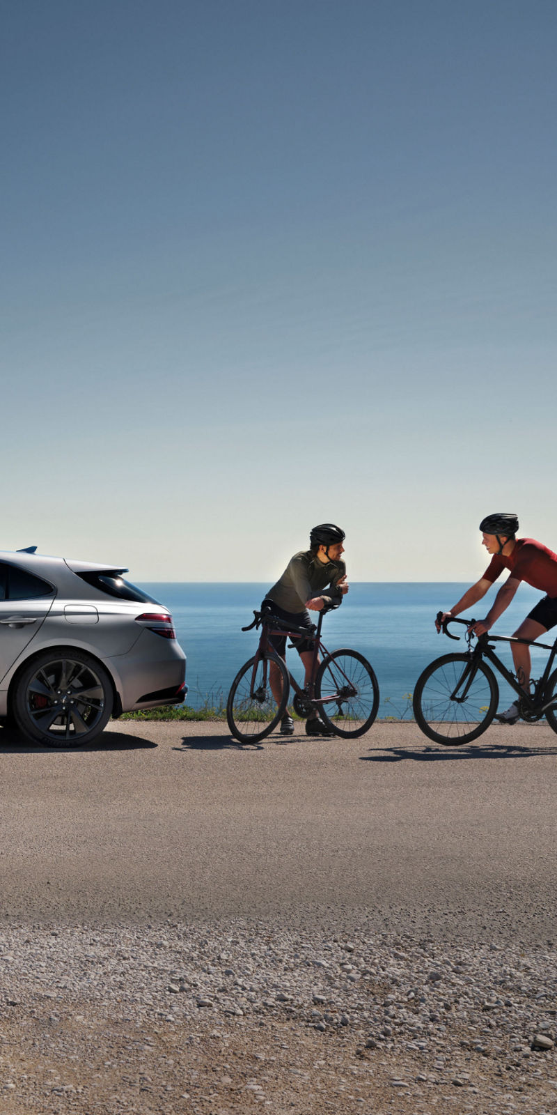 The G70 Shooting Brake parked by the coast with two cyclists nearby, highlighting its sporty and elegant design.