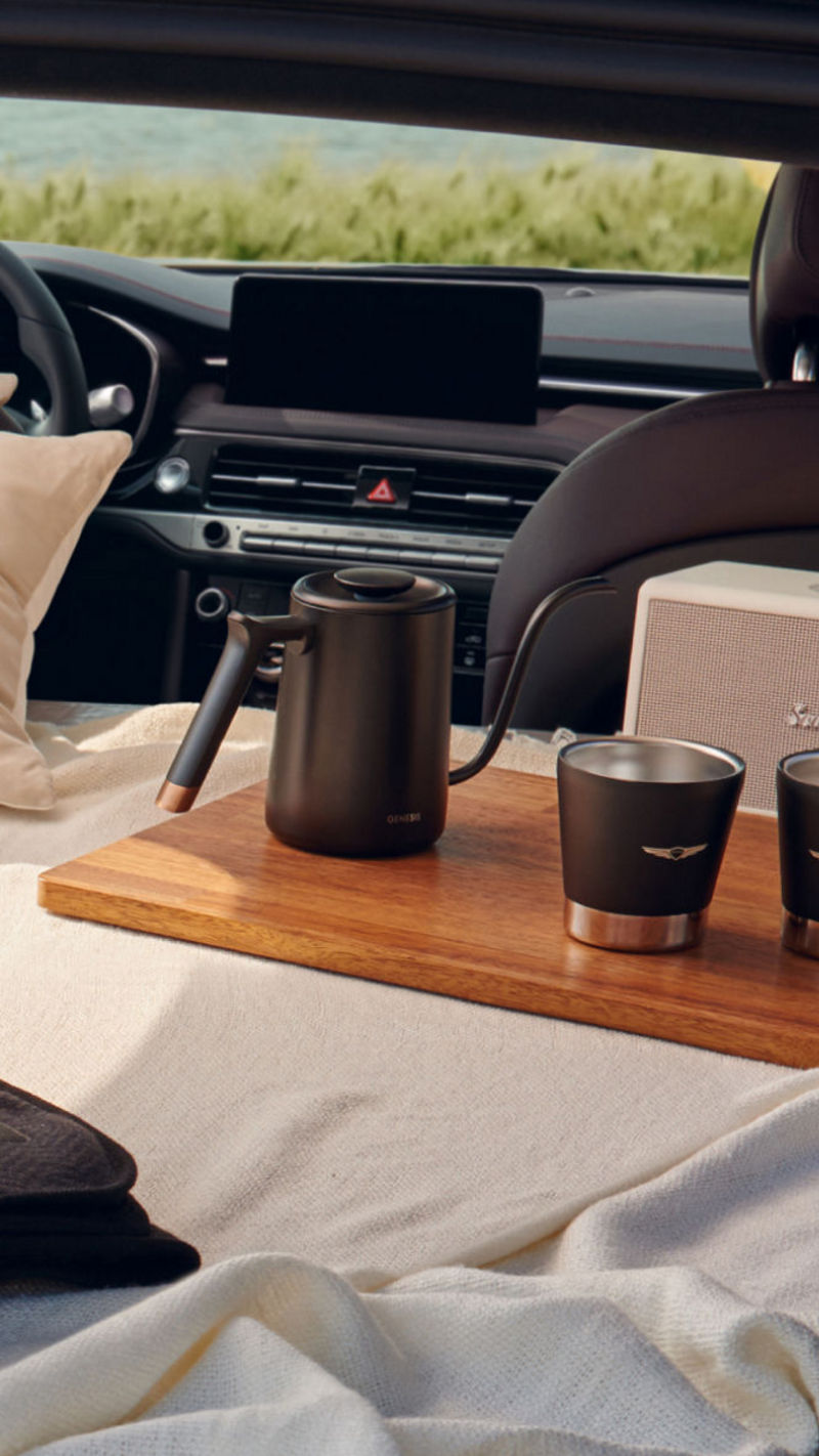 Interior of the G70 Shooting Brake with a cozy setup, featuring a blanket, pillow, and coffee set, highlighting its spacious trunk and comfortable design