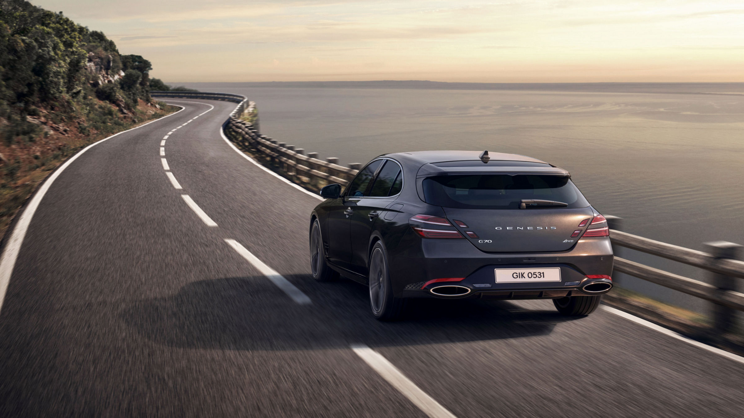 The G70 Shooting Brake driving along a scenic coastal road, showcasing its rear design and dynamic presence.