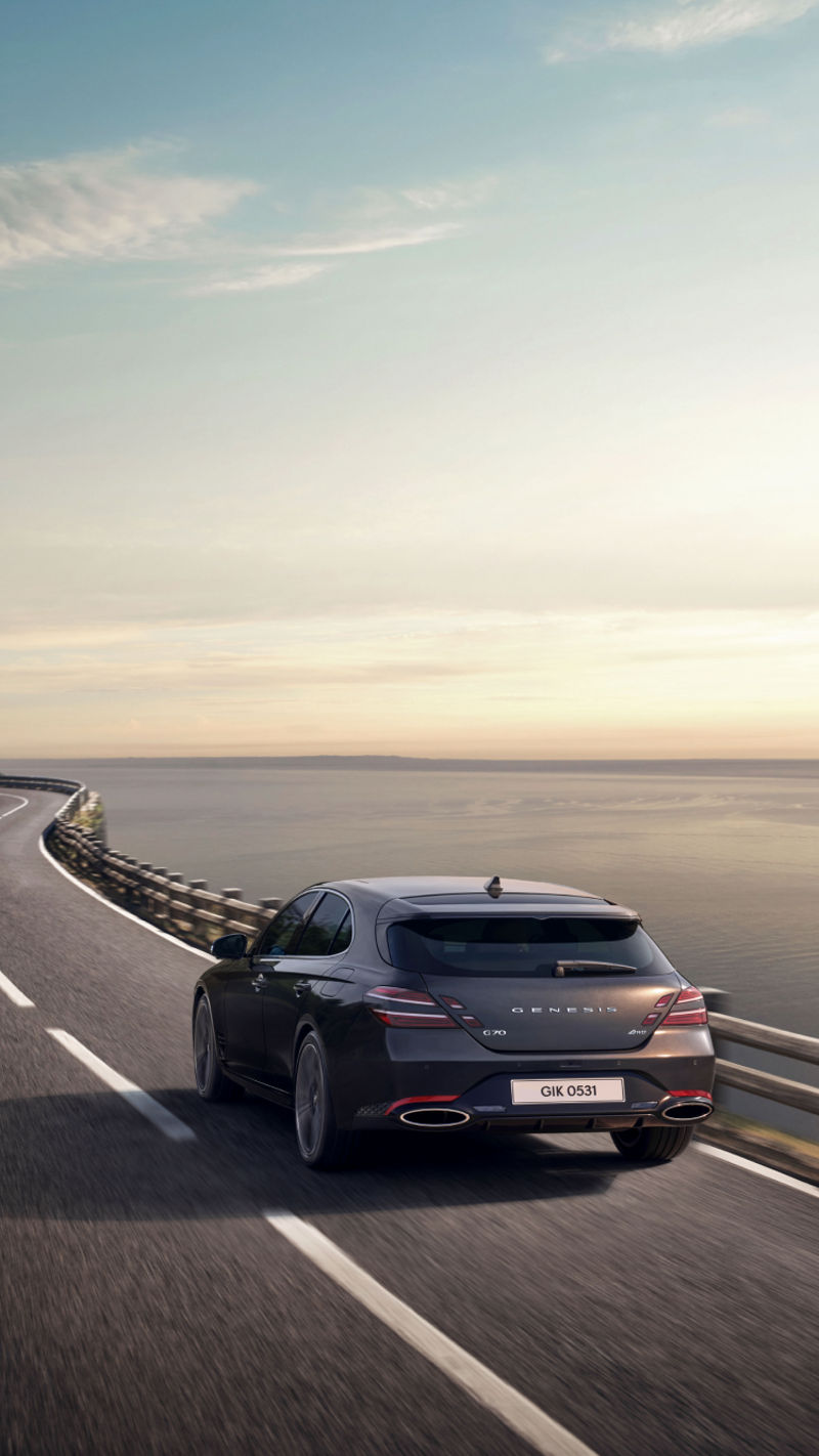 The G70 Shooting Brake driving along a scenic coastal road, showcasing its rear design and dynamic presence.