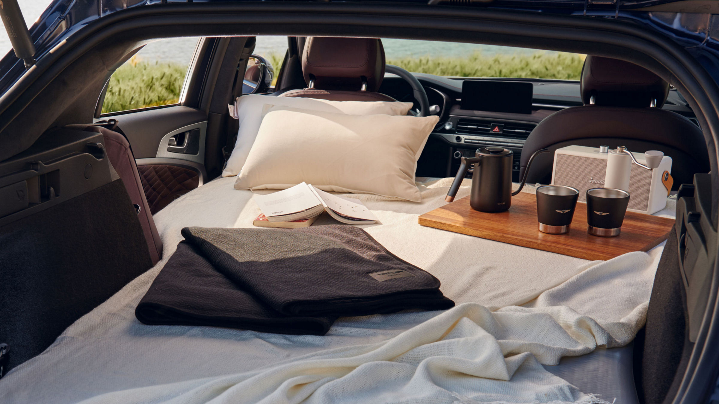 Interior of the G70 Shooting Brake with a cozy setup, featuring a blanket, pillow, and coffee set, highlighting its spacious trunk and comfortable design.