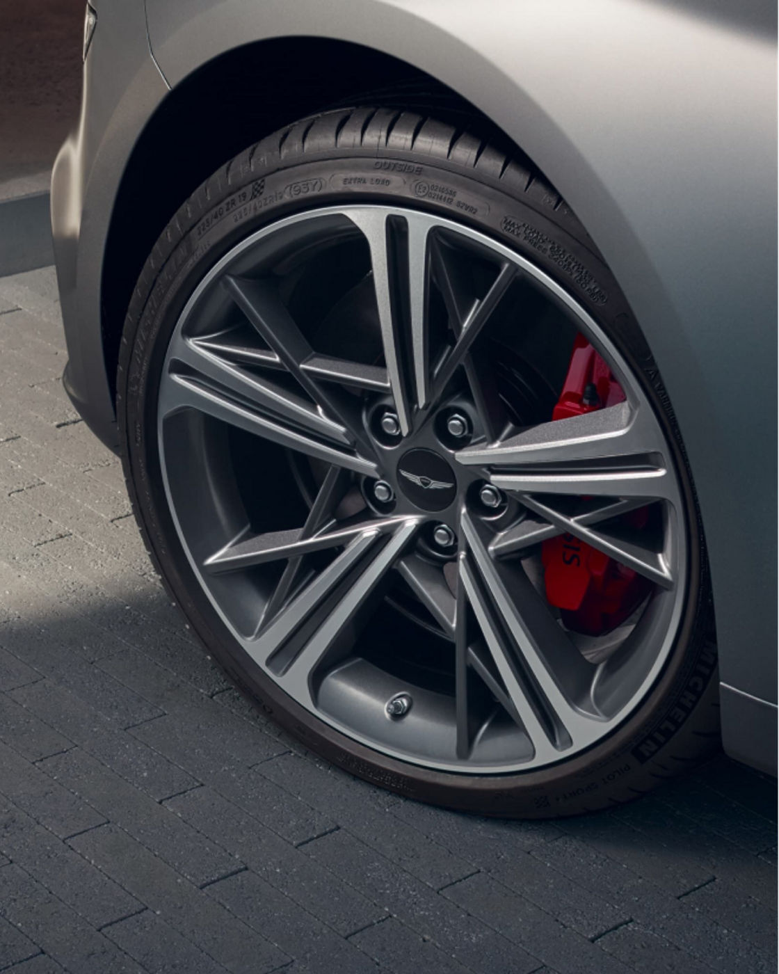 Close-up view of a Genesis G70 alloy wheel and red brake caliper.