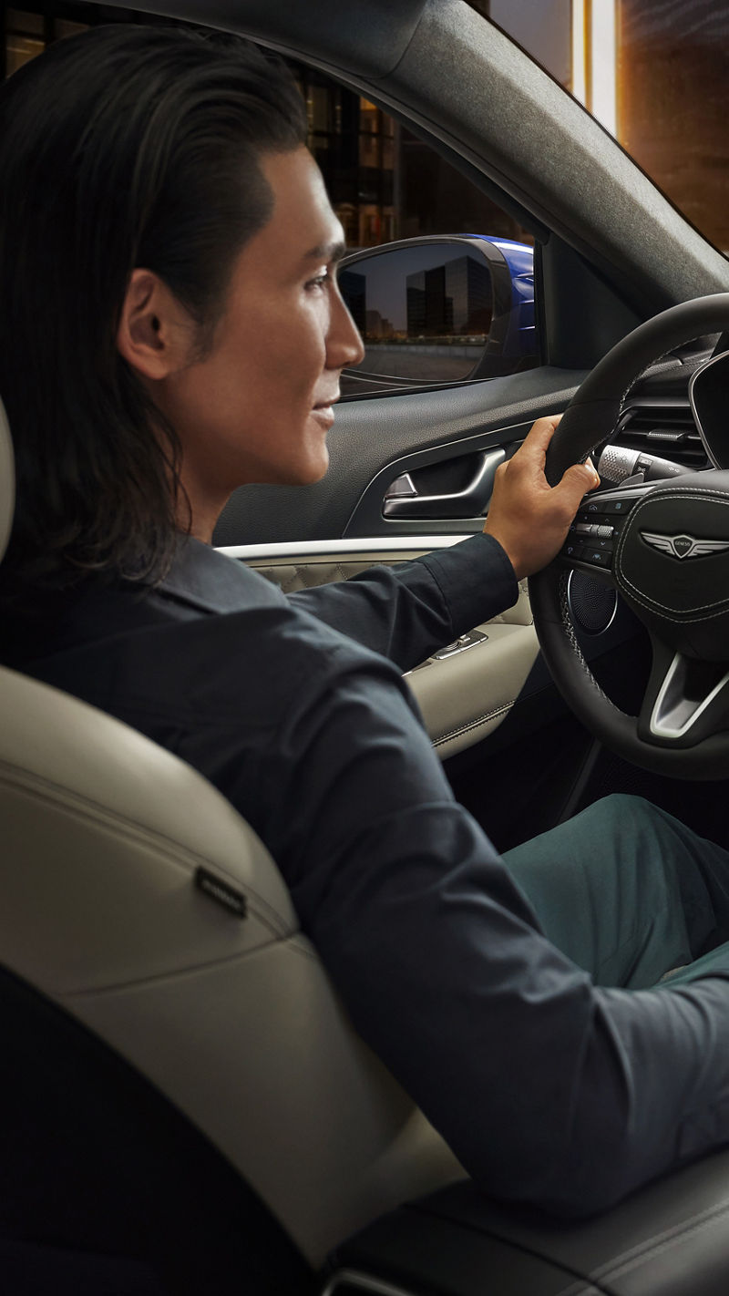 Man at the wheel of the Genesis G70 looks at the display in the centre