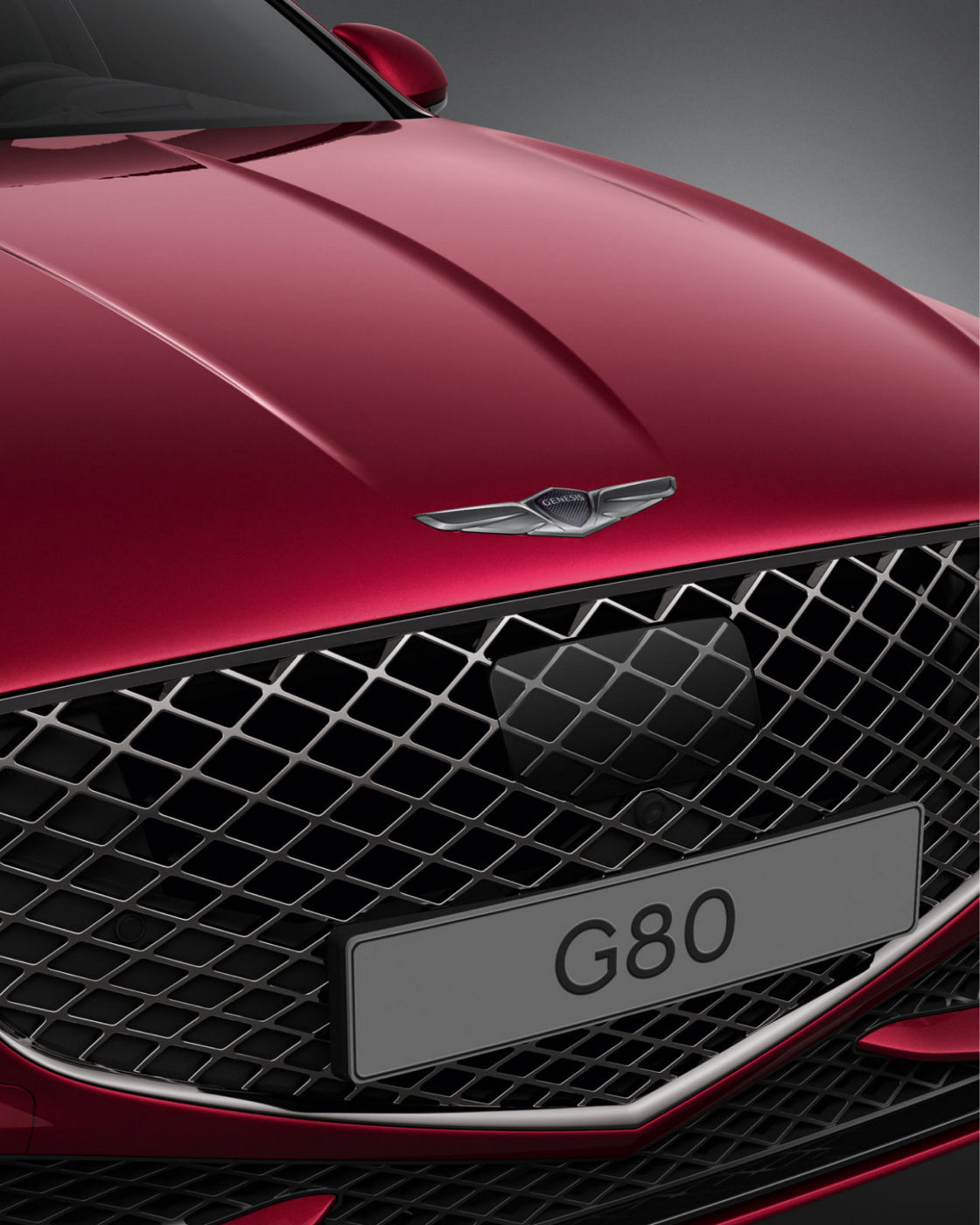 Genesis G80 Sport in red, front view, featuring a black gloss chrome radiator grille.