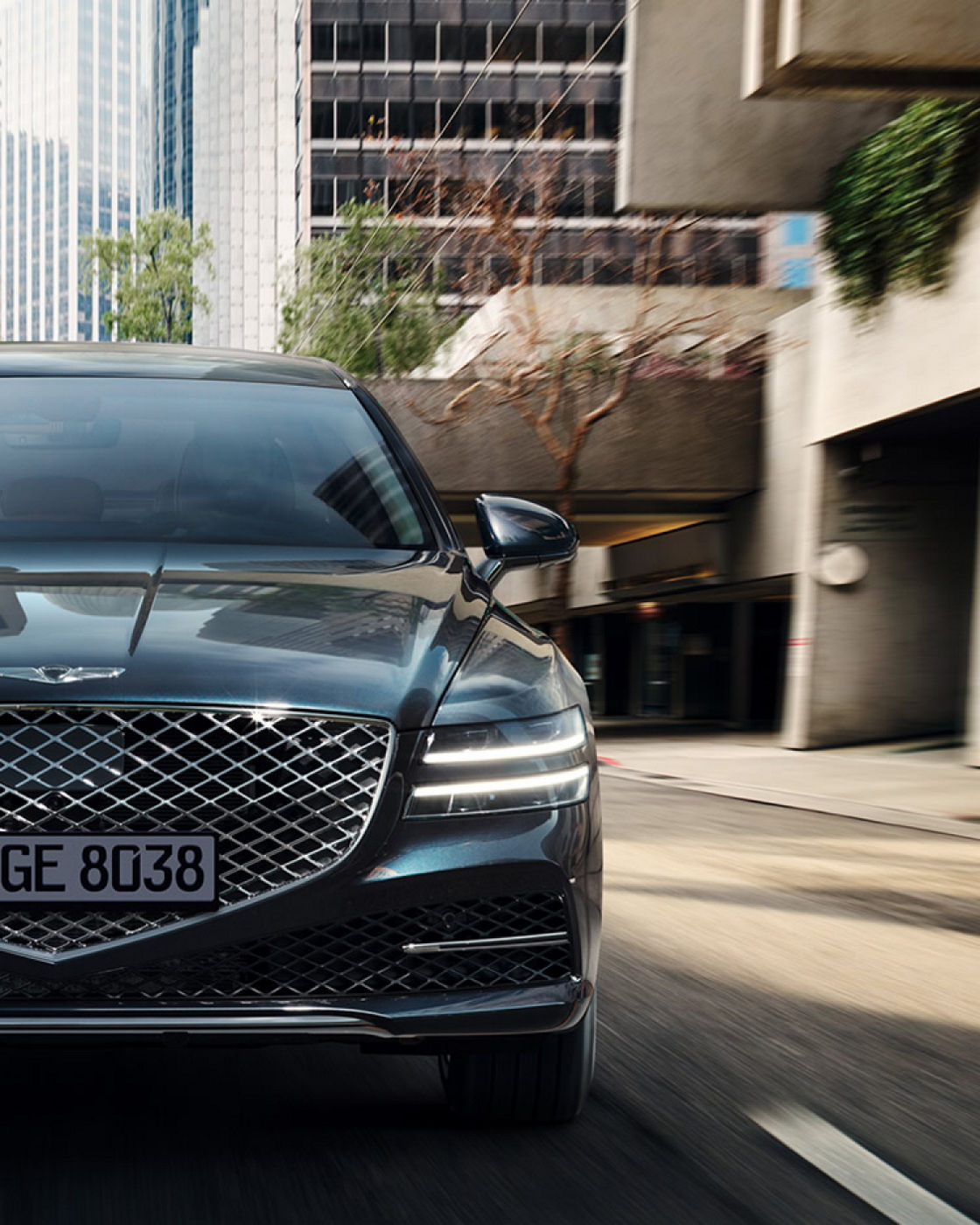 Genesis G80 blue exterior driving through city front view