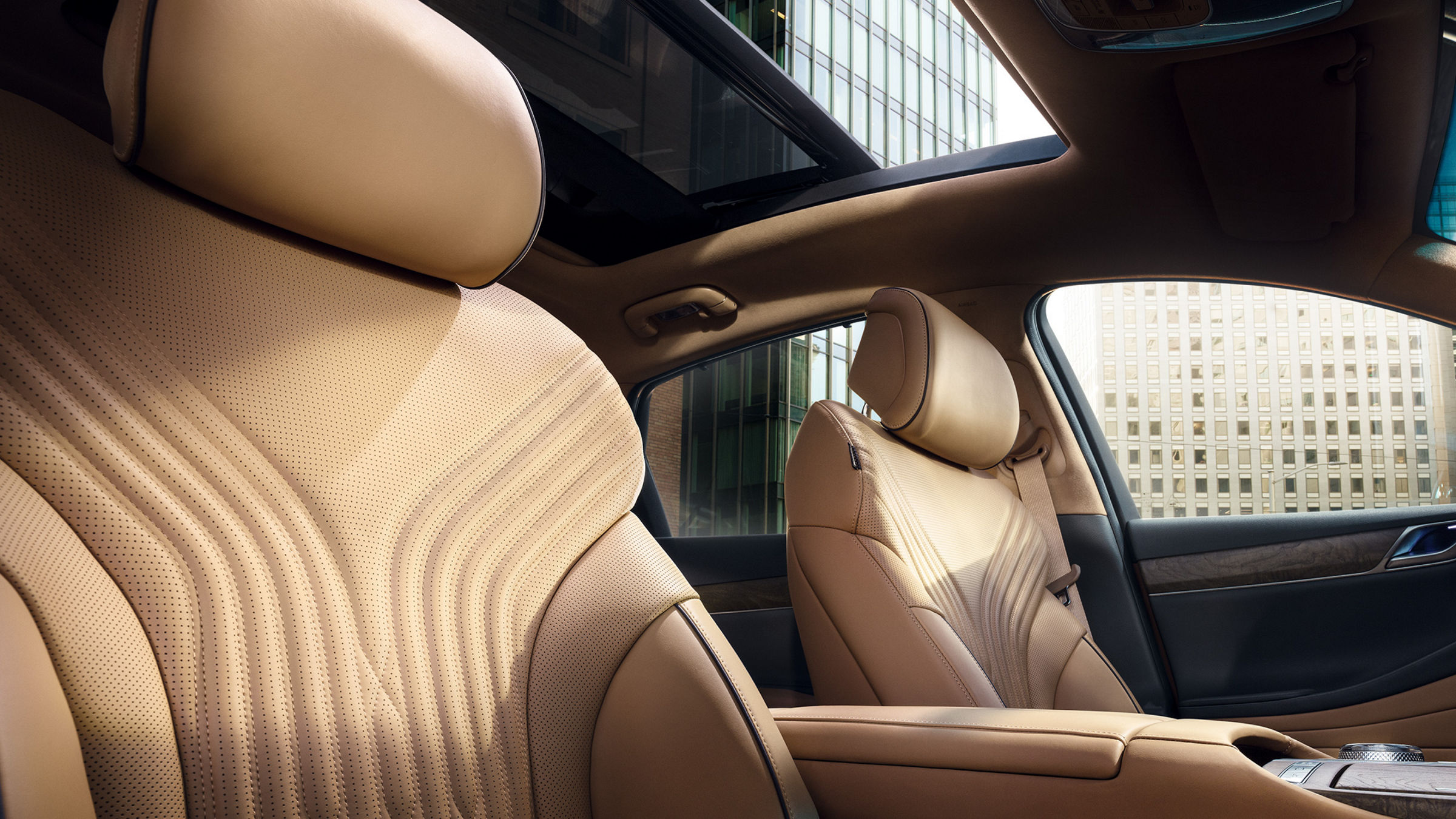 Light brown front seats in a car with skyscrapers in the background.