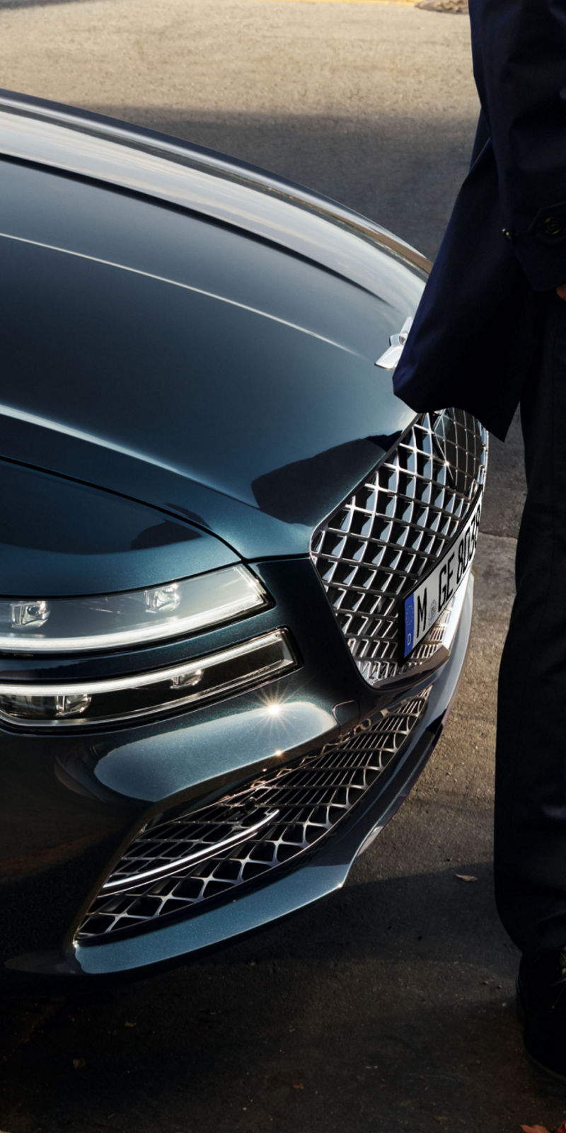 Person standing in front of a Genesis G80 parked at the kerb