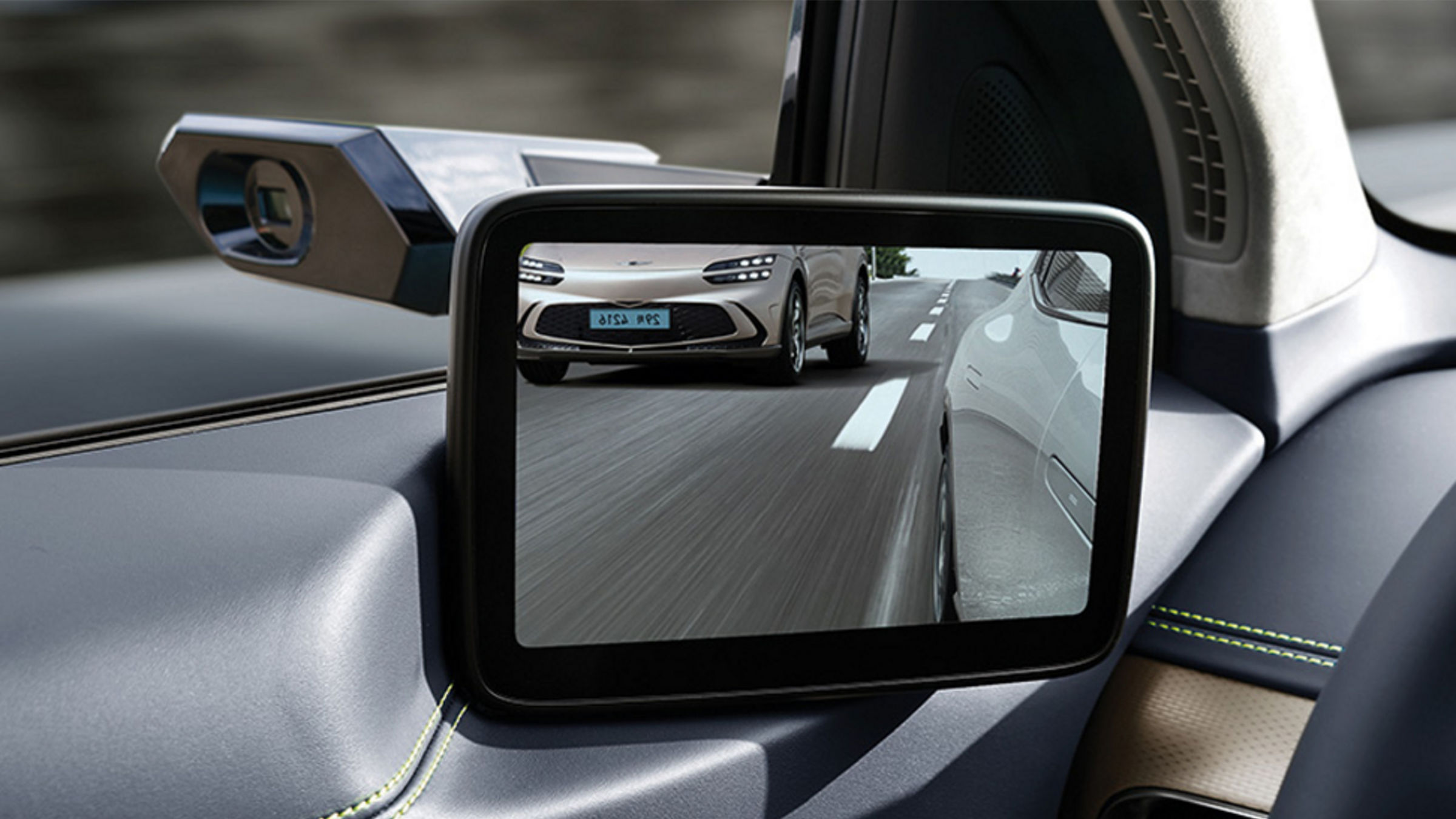 The view of a GV60 in another lane, seen through the digital side mirrors, showcasing Genesis' advanced technology.