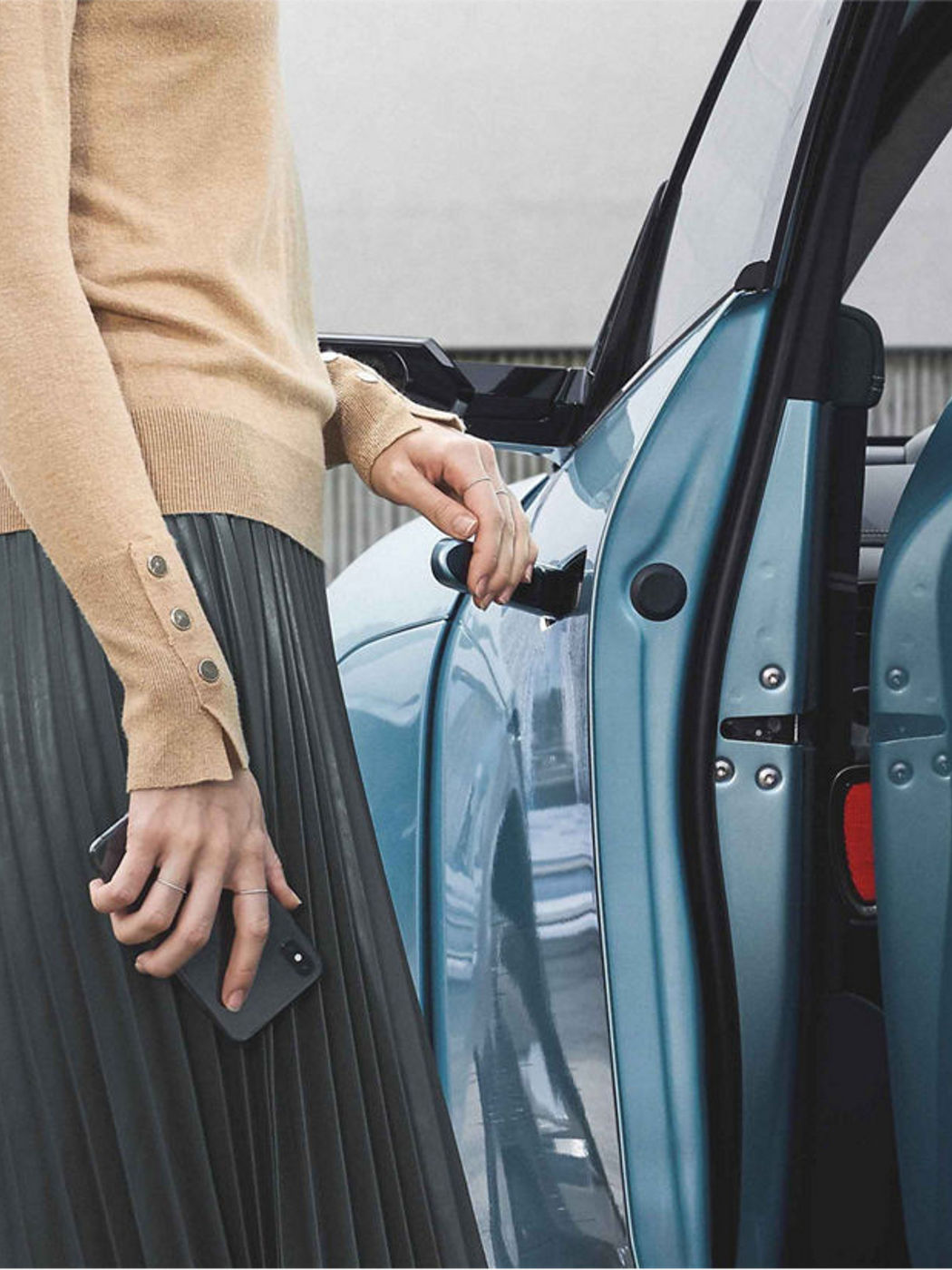 A woman opening the door of the GV60, with the door partially open, showcasing the ease of use provided by the digital key system.