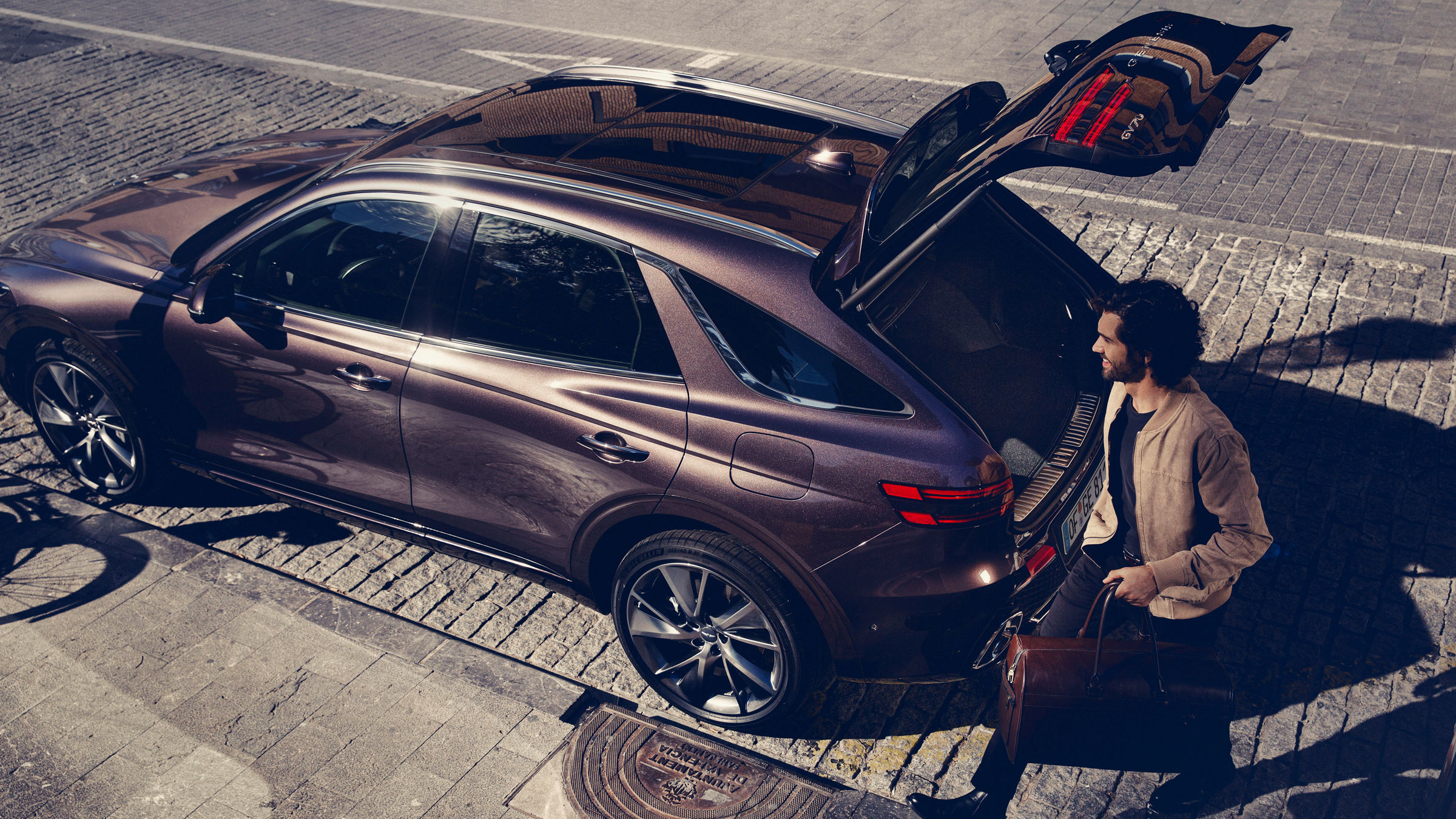 Man with bag in hand next to the open boot of the Genesis GV70