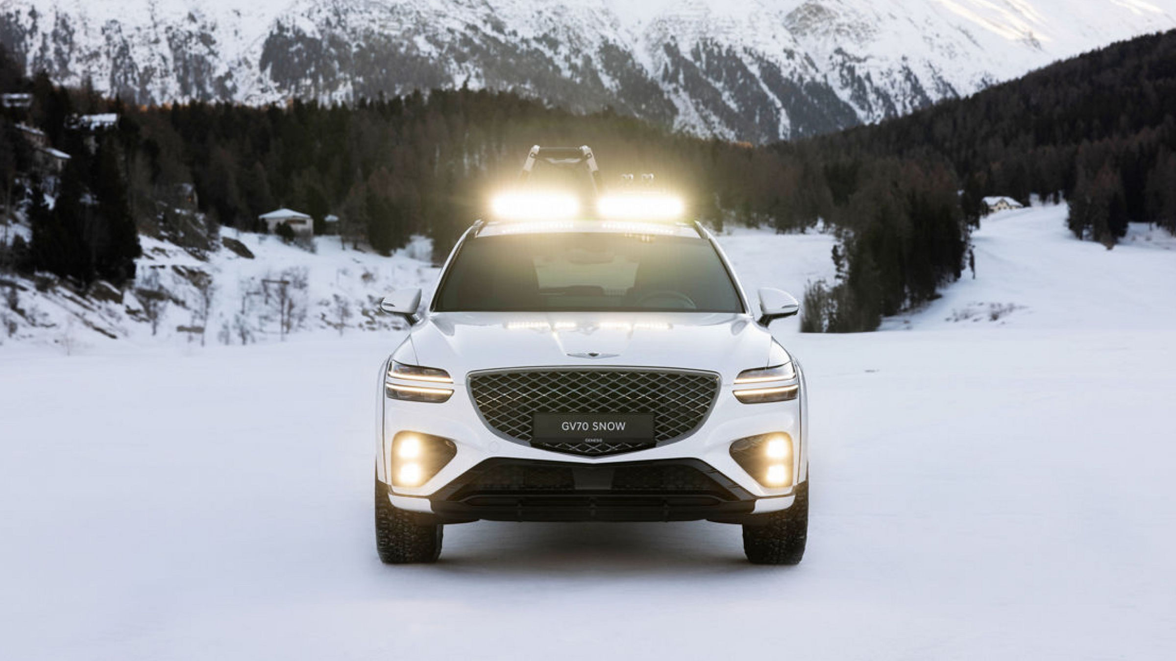 Genesis GV70 Snow Concept white on snow Front view in front of snow-covered mountains