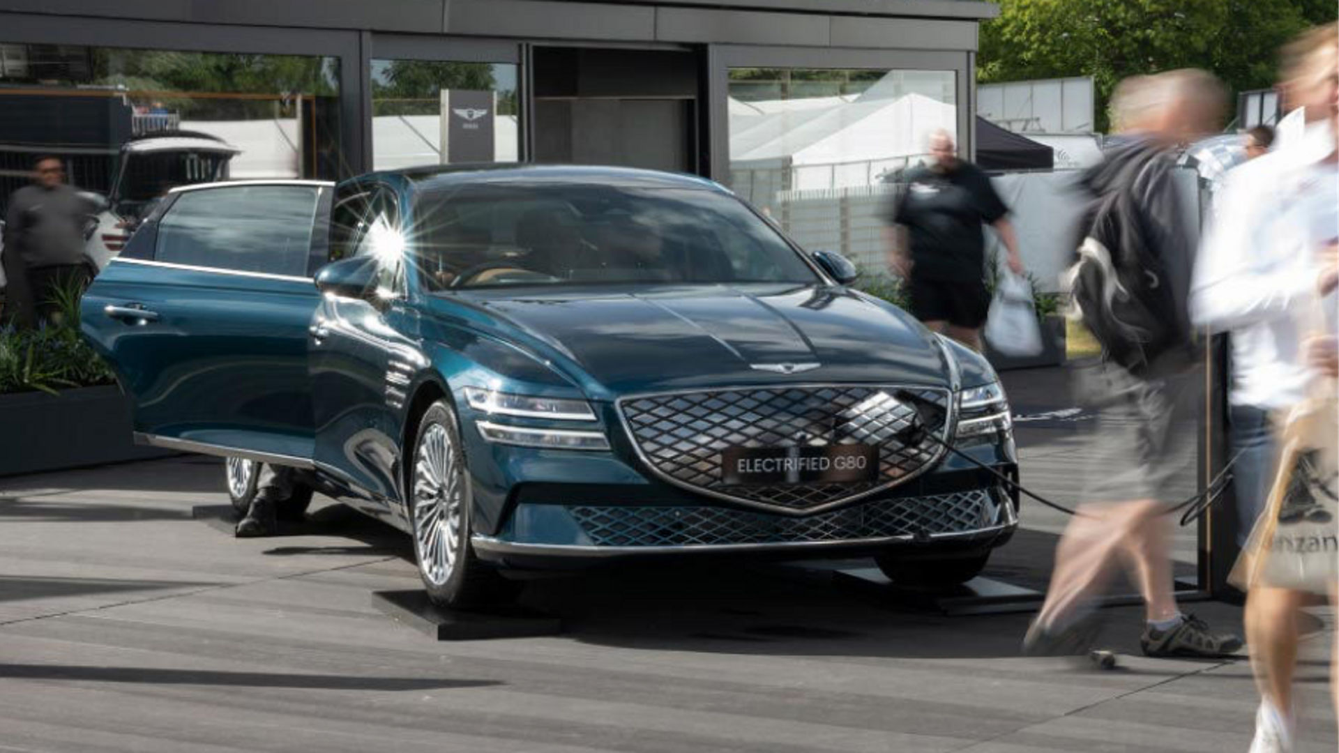 Genesis car in front of a building with people around it