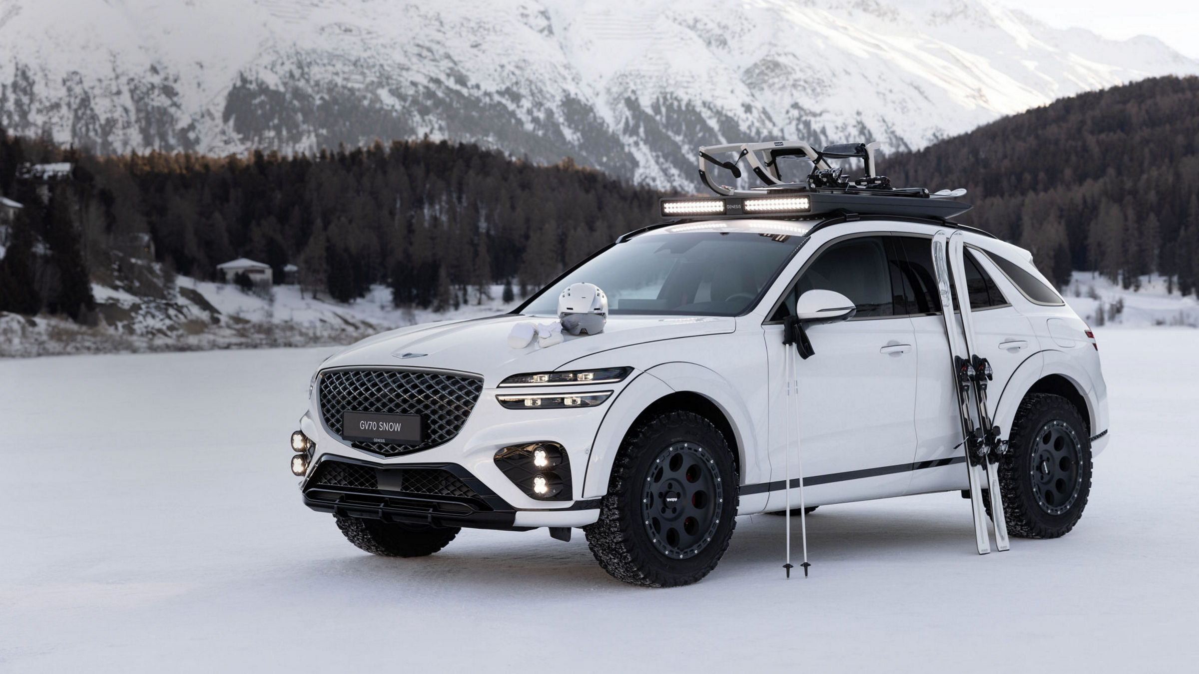 White Genesis GV70 Snow concept on snow with ski equipment in front of snow-covered mountain