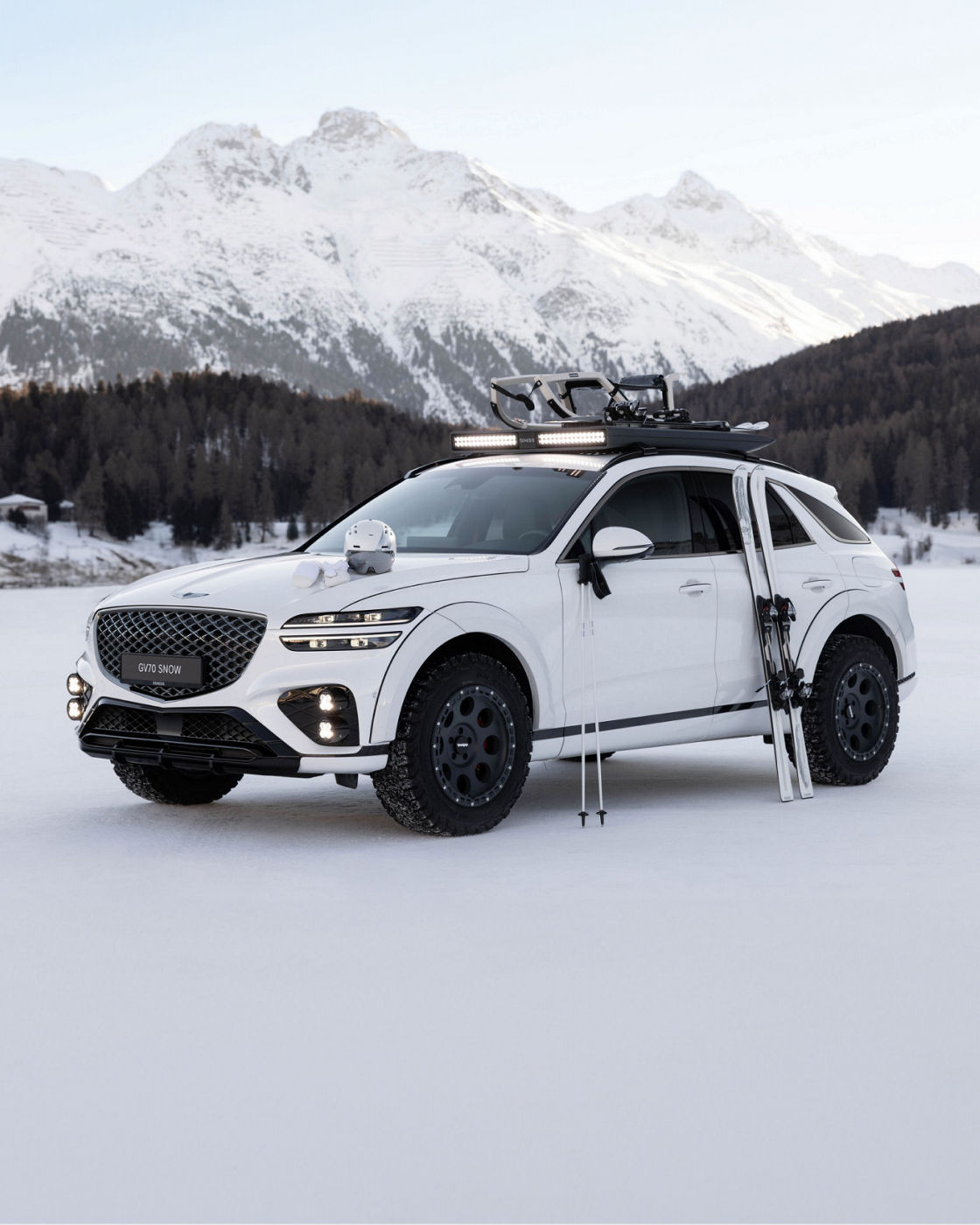 White Genesis GV70 Snow Concept on snow with ski equipment in front of snow-covered mountains