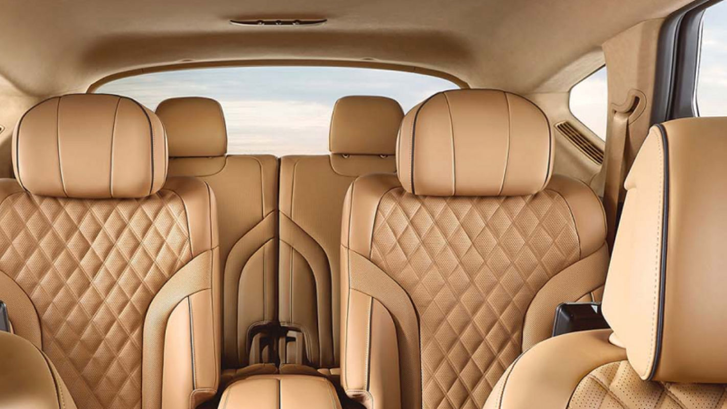 View of the rear interior of a Genesis with diamond-patterned beige leather seats, emphasizing luxury.