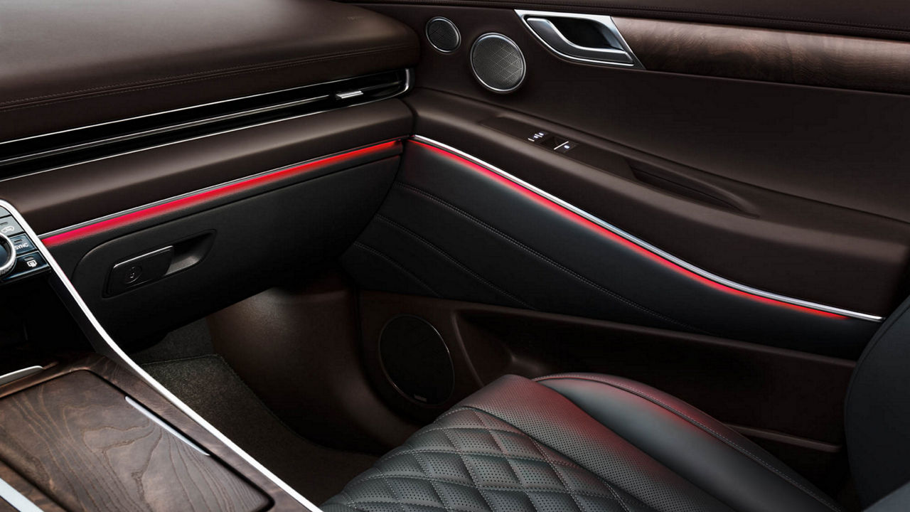 Innenansicht des Genesis GV80 mit beigen, gesteppten Ledersitzen, einer breiten Mittelkonsole und einem modernen Armaturenbrett mit Digitalanzeige.