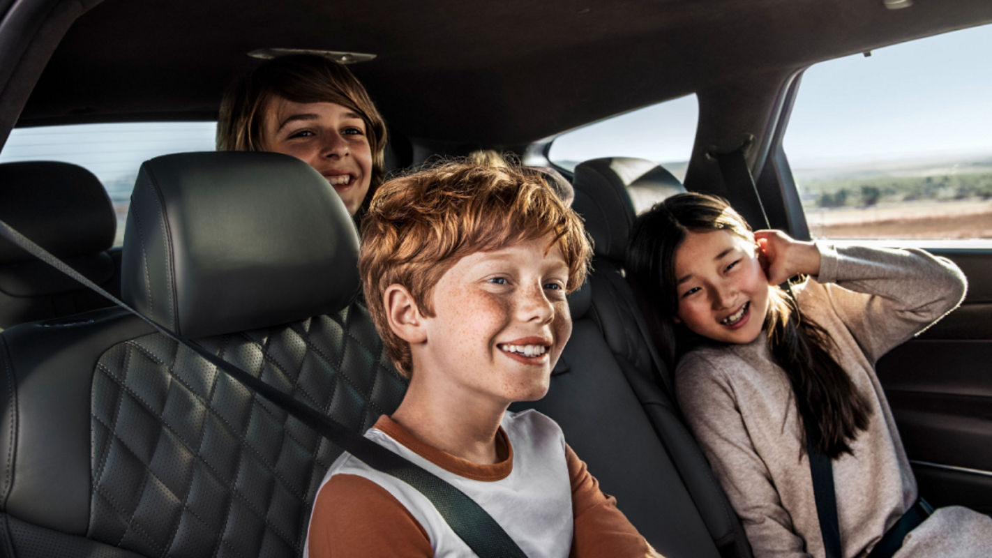 Three children seated in the rear of the Genesis, laughing and enjoying their journey.