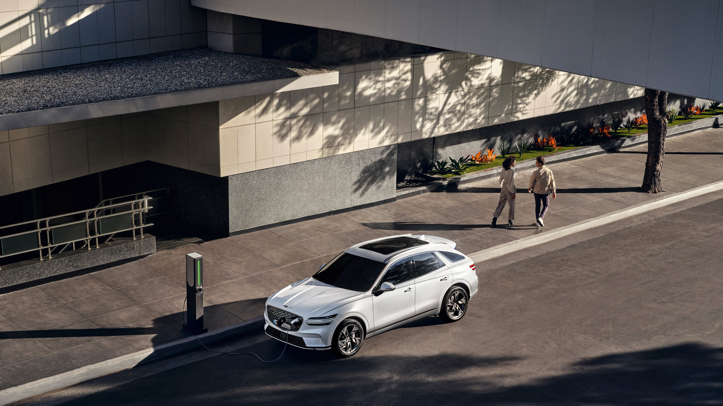 Genesis GV60 in white is parked at a charging station in the city