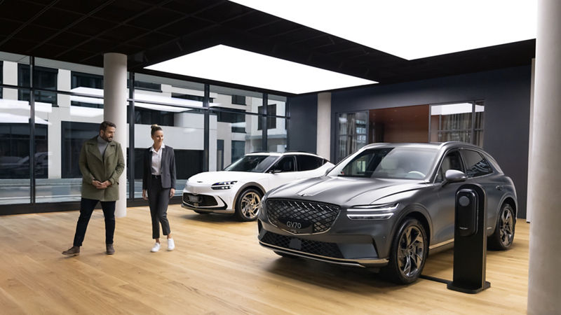 A Genesis GV70 in grey next to a GV60 in white in the Genesis Studio Frankfurt