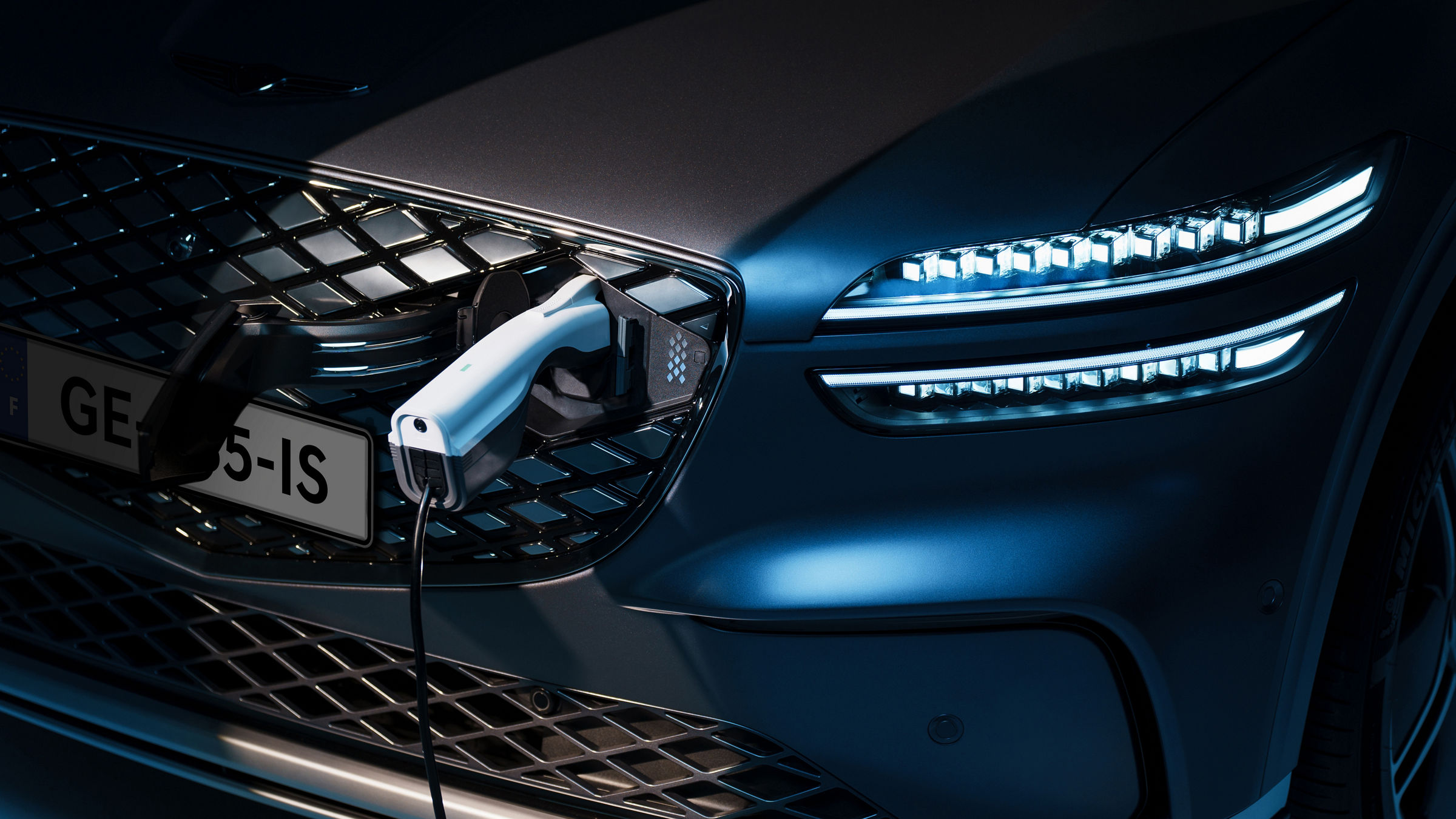 A charger is plugged into the front charging port of a Genesis electric vehicle.