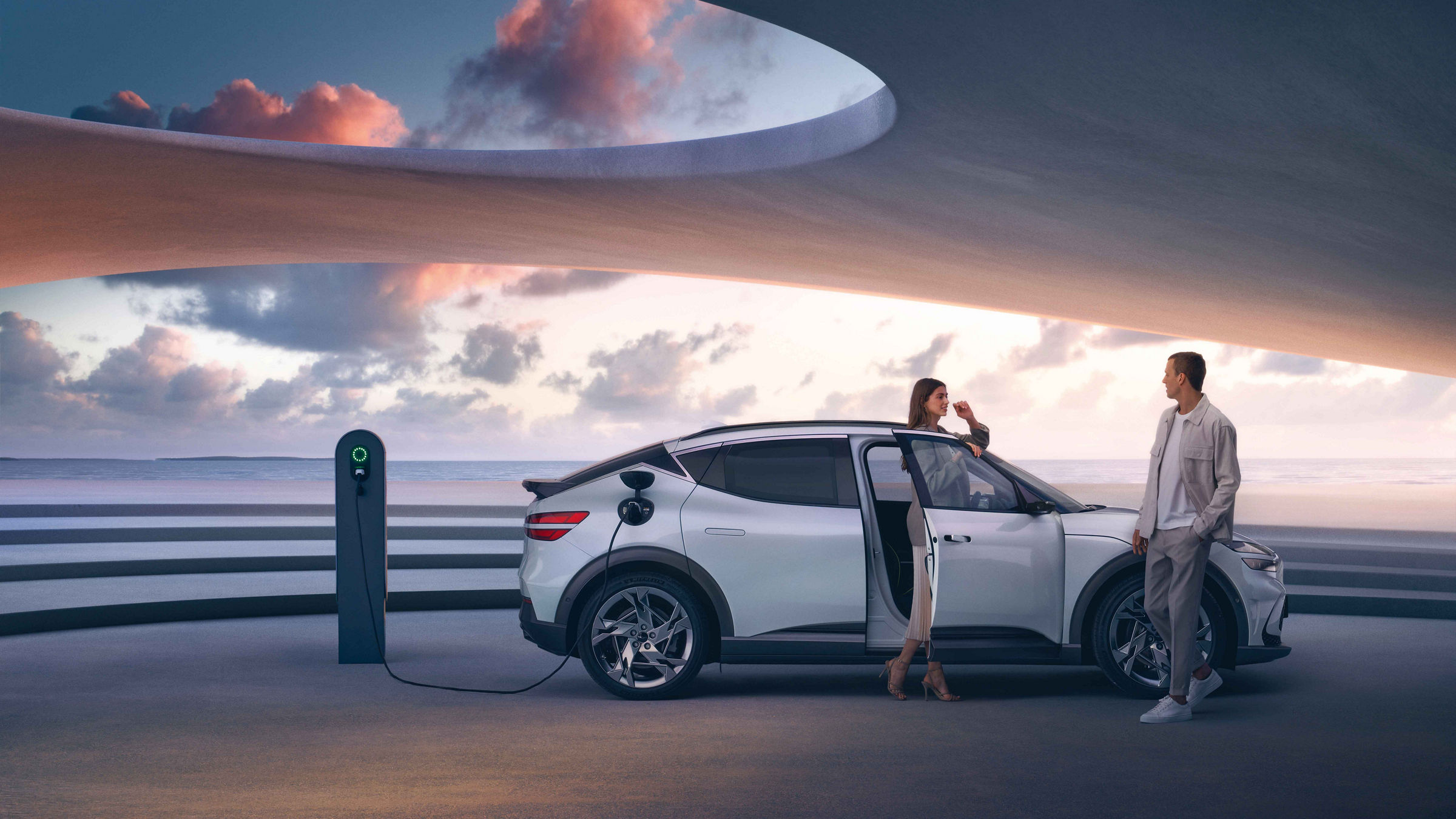 Man and woman next to an electric car parked at a charging station by the sea