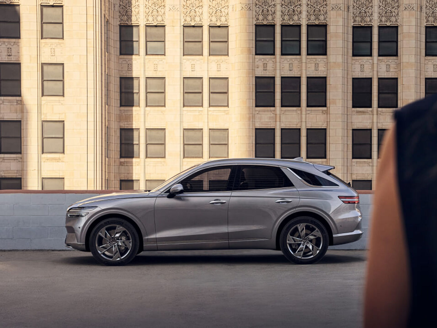 Back of a woman with a Genesis car in front of a house wall in the background