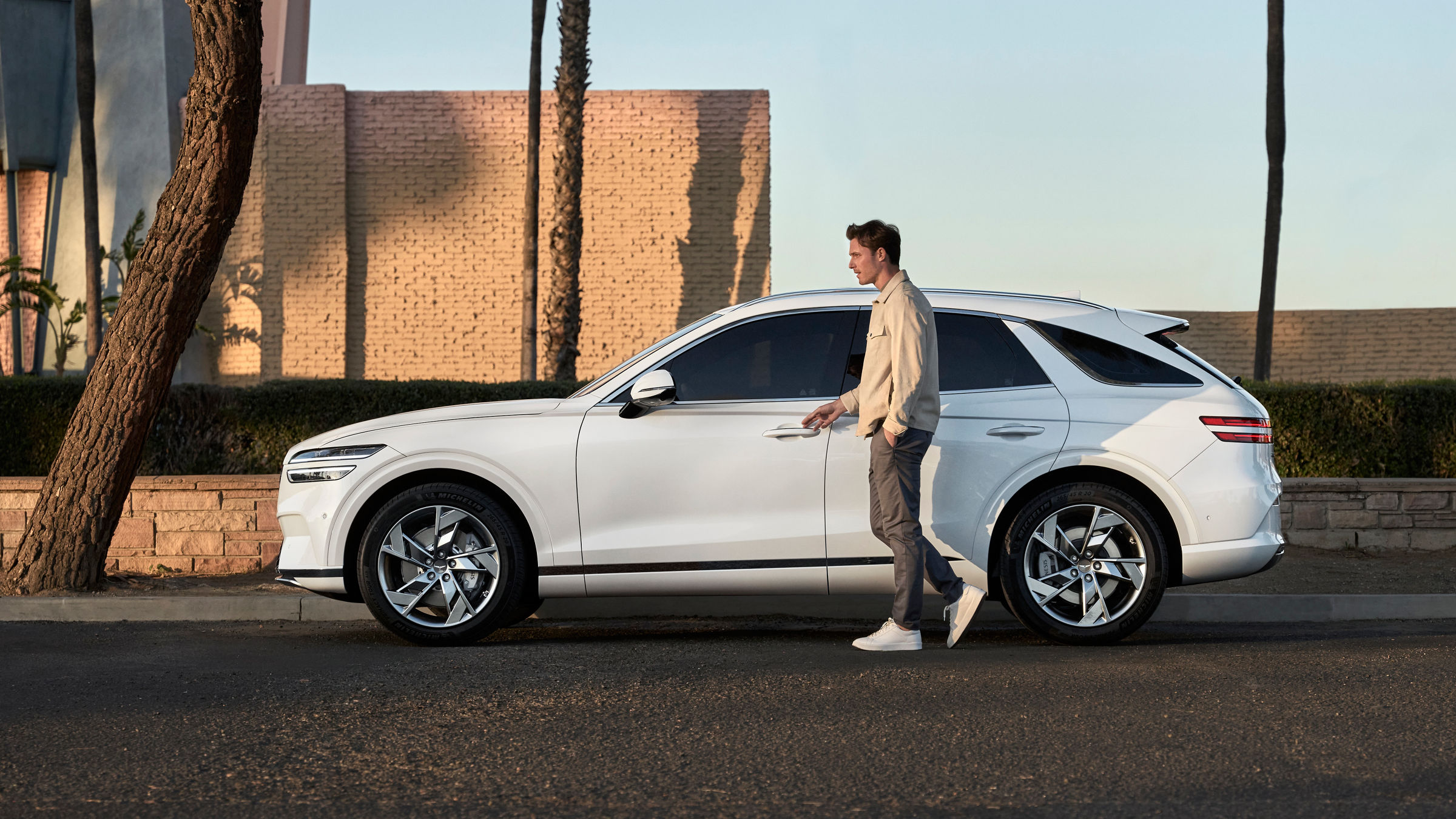 White Genesis GV70 from the side with a man at the driver's door