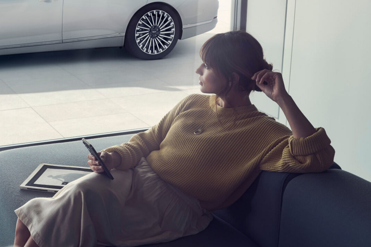 Woman on a sofa with a mobile phone in her hand looking out of the window