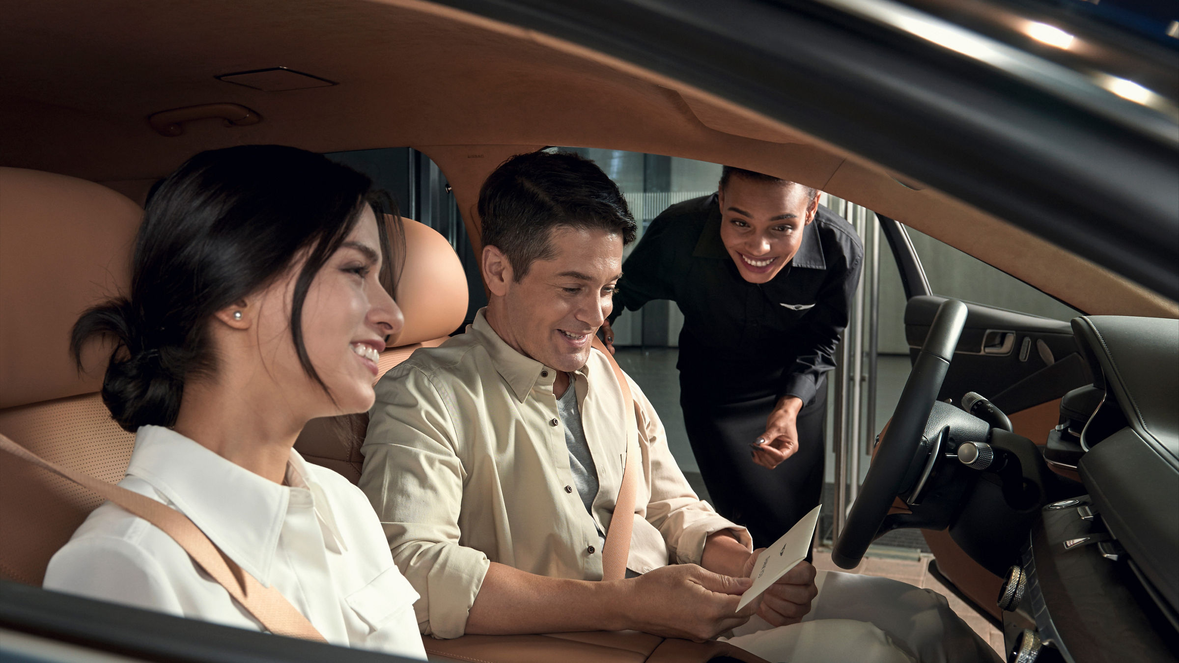 Man and woman in a car with a salesman next to them