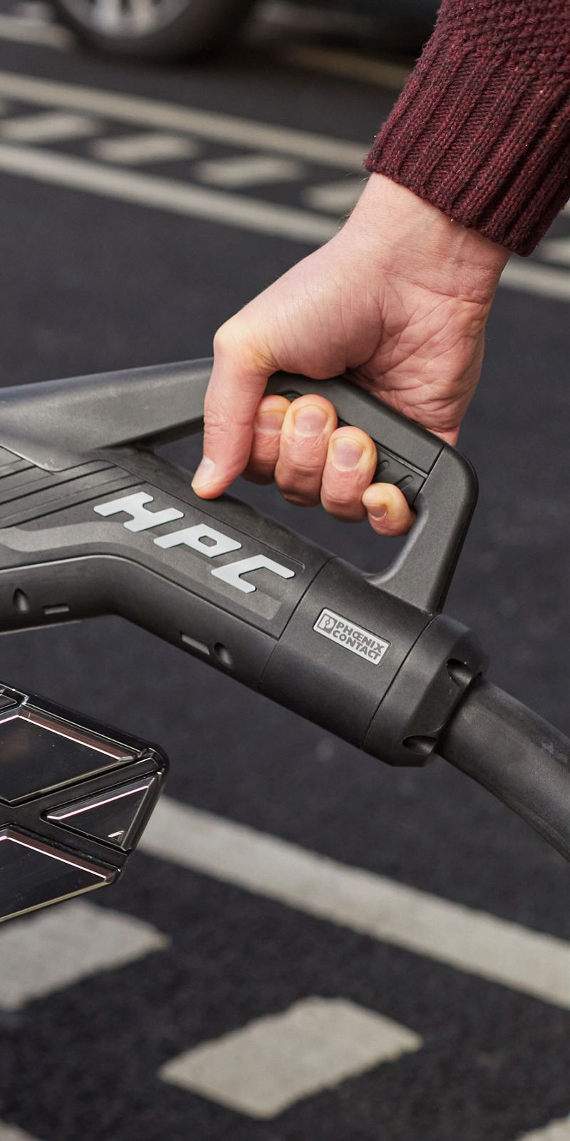 A hand plugs a charging cable into an electric car