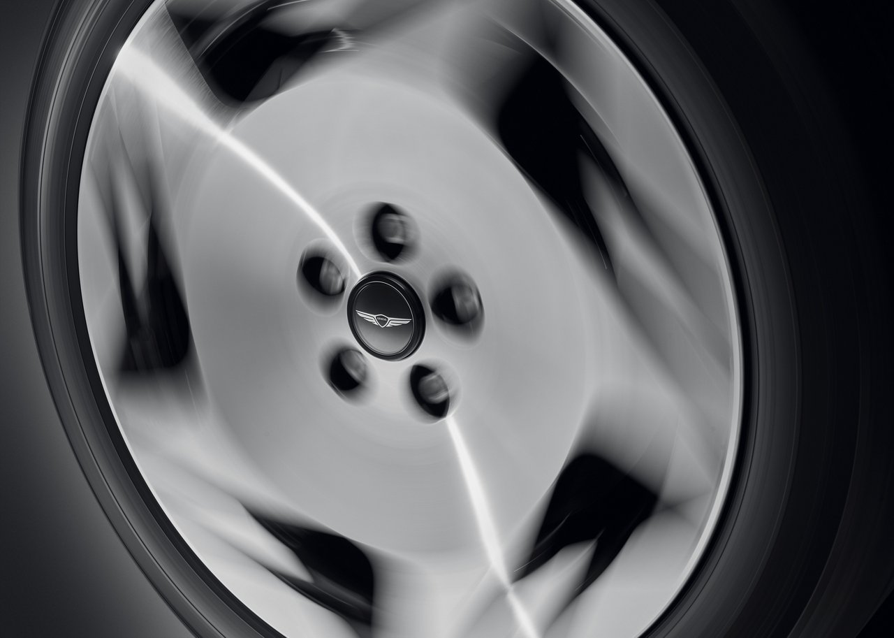 The Genesis logo is clearly visible in the center as the floating wheel cap is spinning.