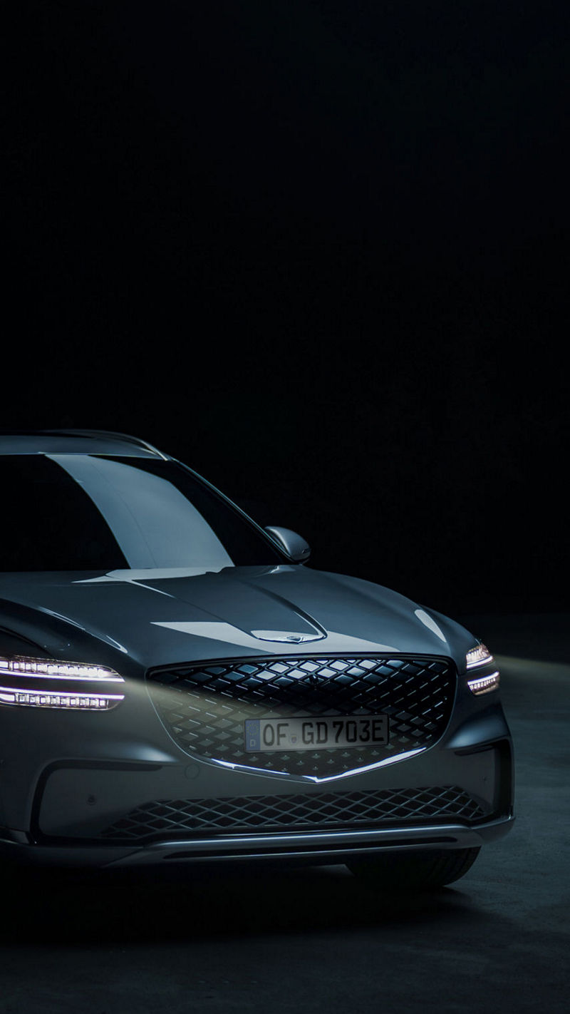 El Genesis Electrified GV70 está aparcado en un espacio exterior con una superficie de hormigón vista.