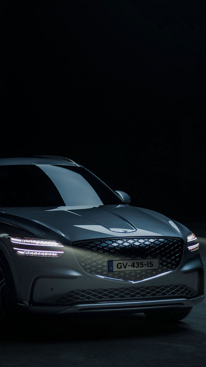 Genesis Electrified GV70 is parked in an outdoor space with an exposed concrete surface.