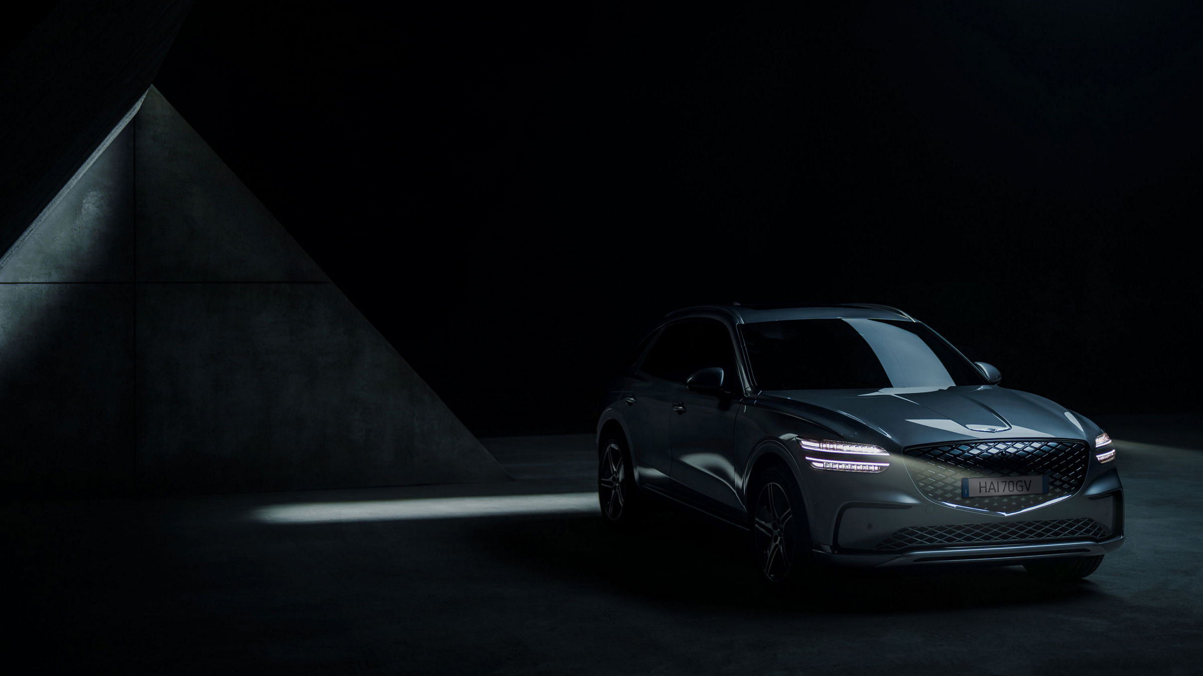 La Genesis Electrified GV70 è parcheggiata in uno spazio esterno con una superficie in cemento a vista.