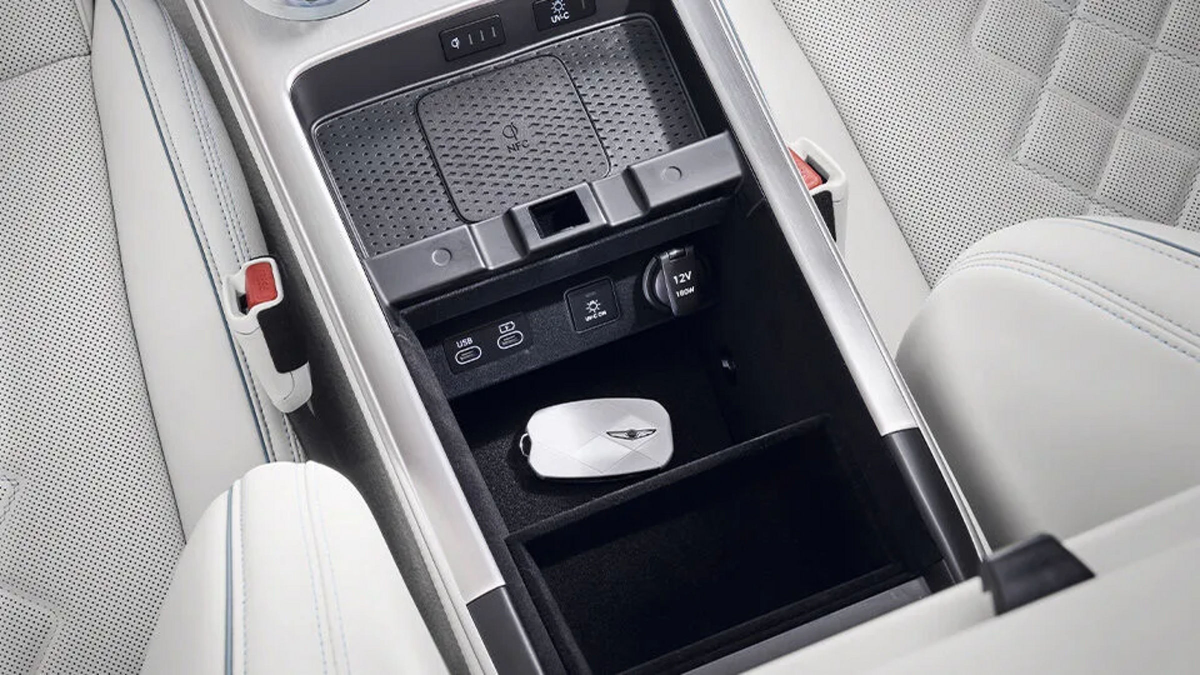 A view of the console between the driver and front passenger seats. The vehicle's physical key is stored inside the compartment.