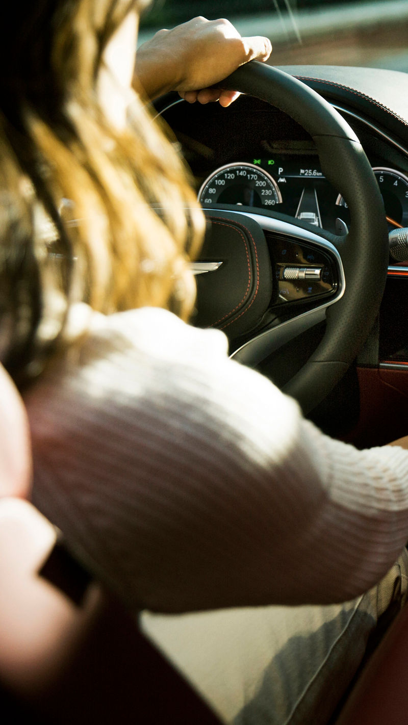 A woman at the wheel of a car switches on the air conditioning