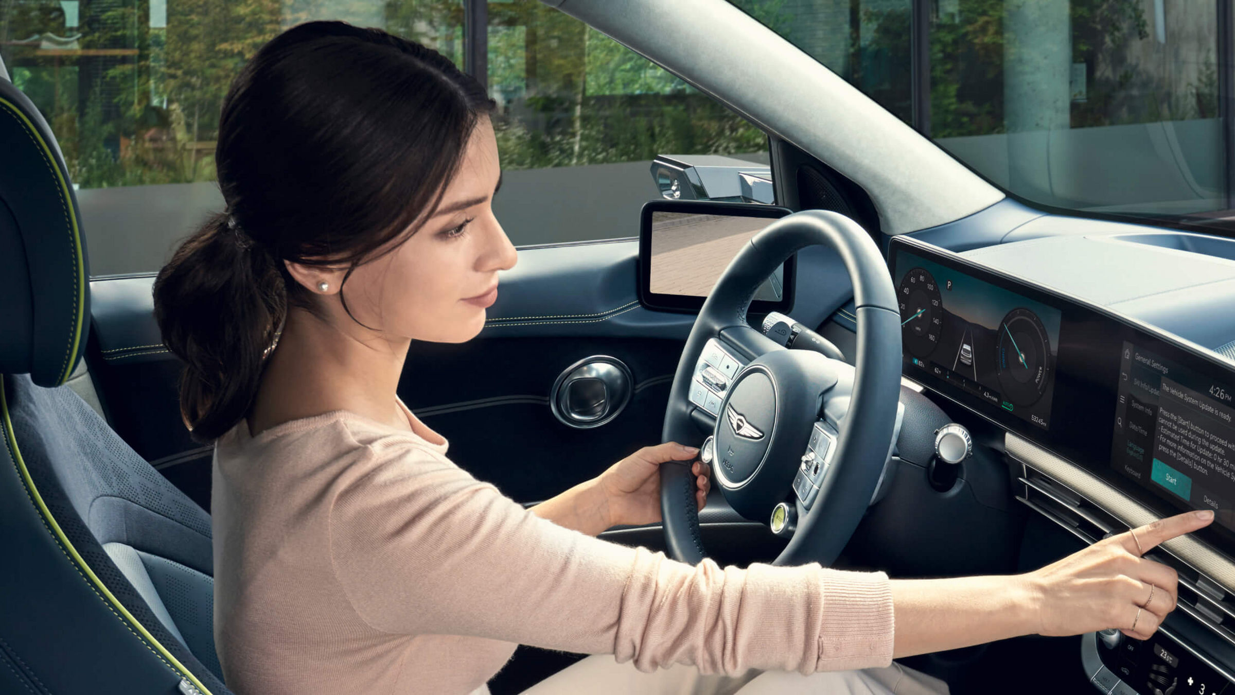 Woman in the driver's seat of the Genesis GV60, operating the display above the centre console