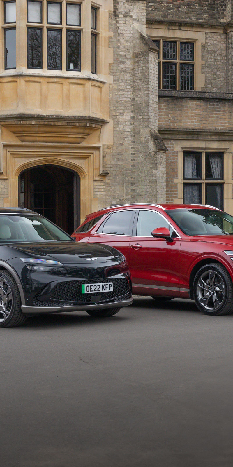 Three Genesis cars in black, red and blue in front of a building