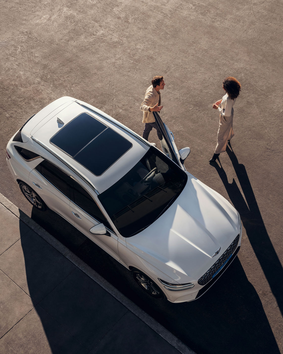 White Electriefied GV70 is parking on the road with two people next to it - top view