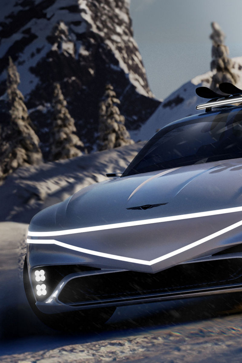 Genesis X Snow speedium concpet car sits stop a snowy mountain. Its front can be seen, with headlights lit up