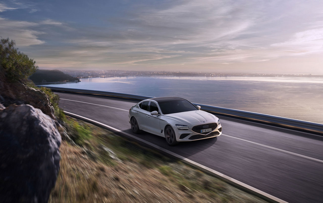 White Genesis G70 on a road by the sea