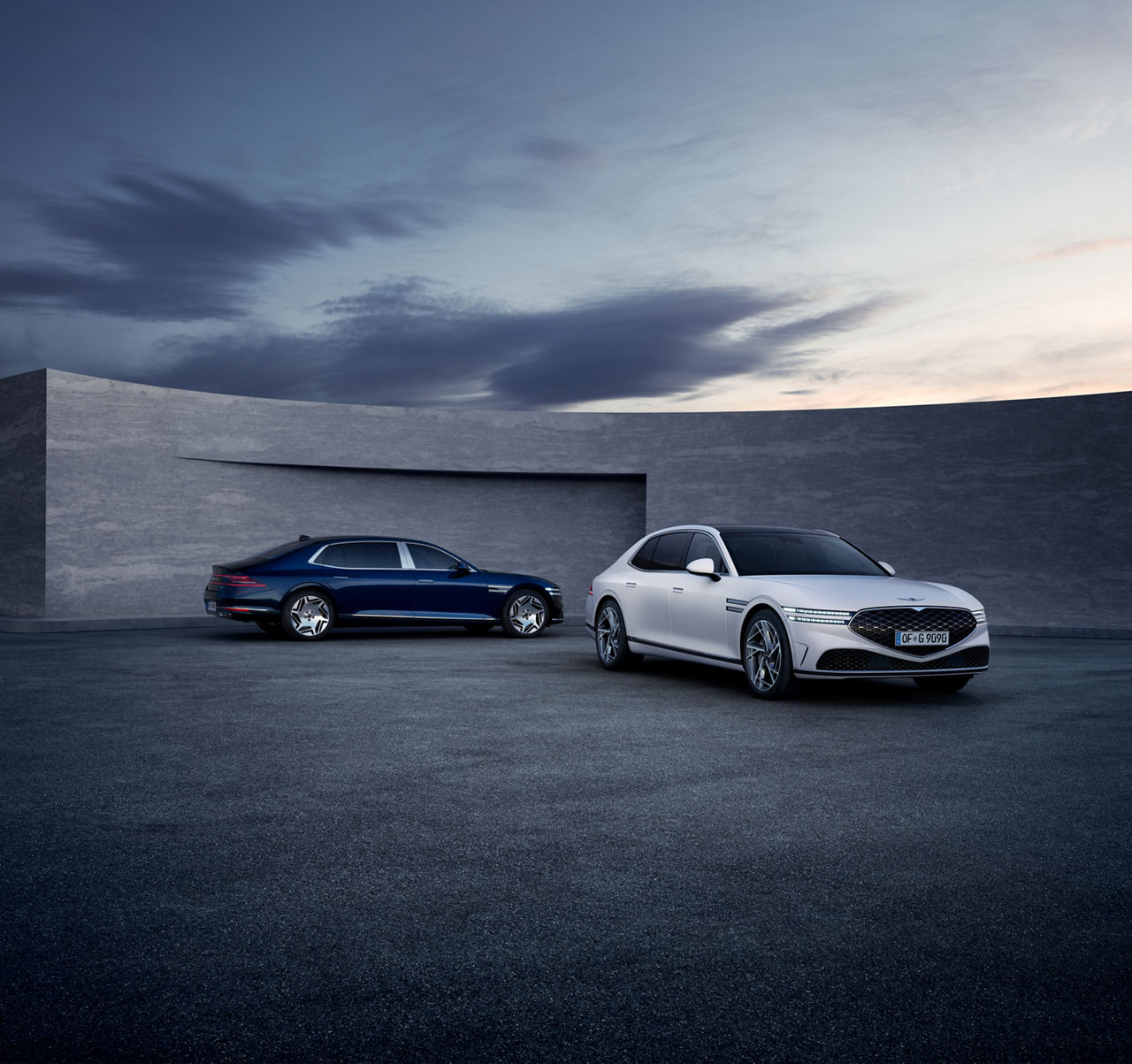 A white and a blue Genesis G90 in front of a grey wall