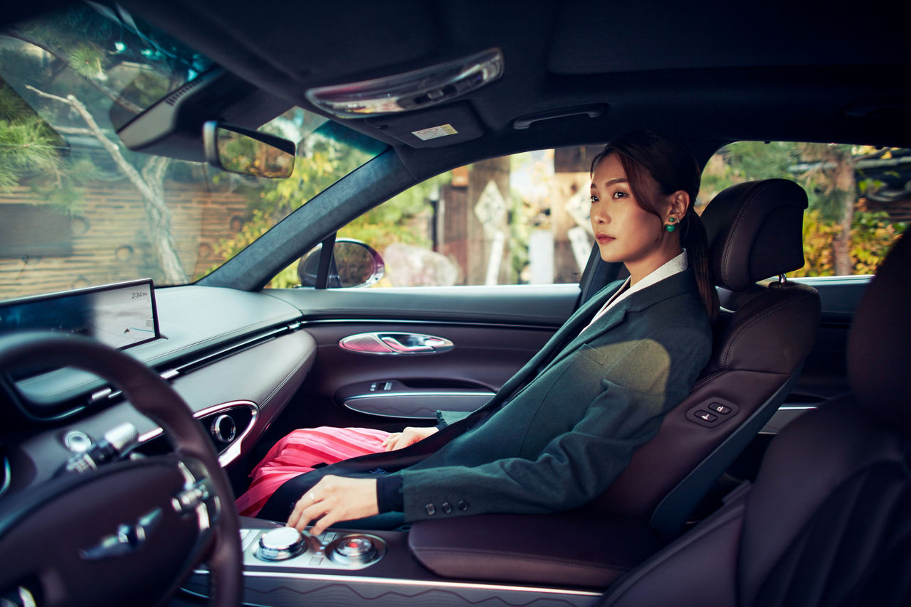 Woman in the passenger seat of a Genesis GV70 looks outside 