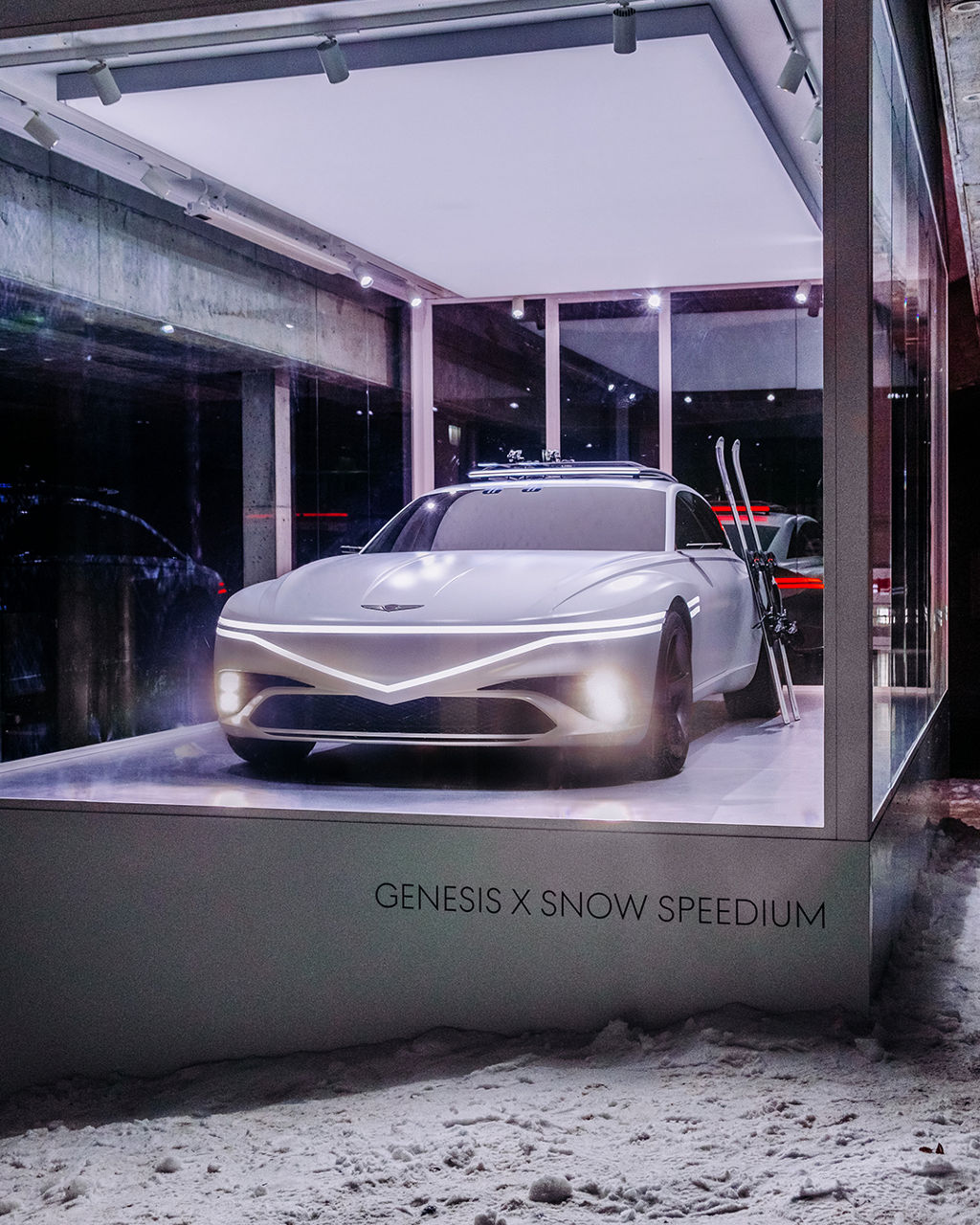 Gläserner Ausstellungsraum mit dem Genesis X Snow Speedium umgeben von Schnee