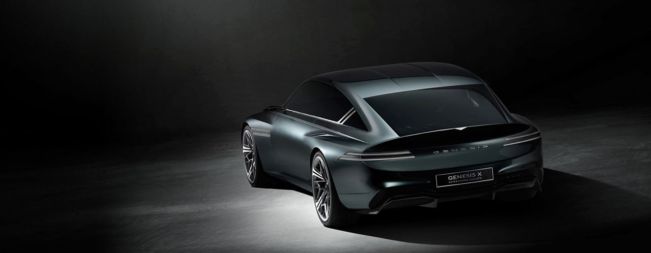 Genesis X Speedium Coupe in black from diagonally behind in dark surroundings