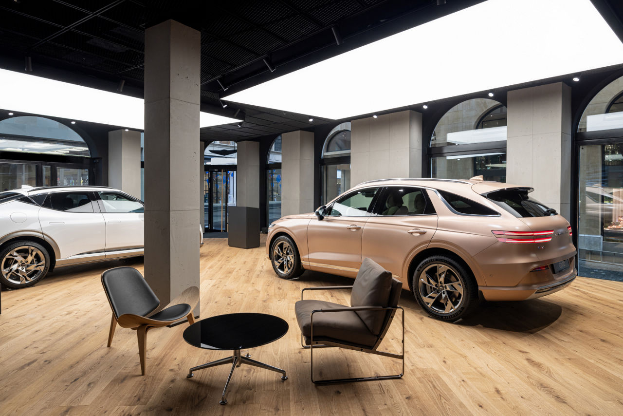 Two chairs and a table in front of two Genesis cars in a Genesis studio