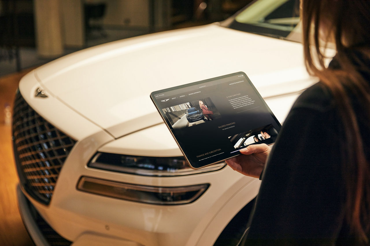 Woman with an Ipad in her hand in front of the front part of the Genesis GV70